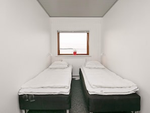 A small, narrow room with two single beds, a window with a view, and a radiator. - 10 Person Holiday Home in Farso (Farso)
