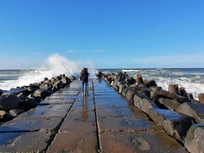 A stone pier extending into the sea with waves crashing against it. - 6 Person Holiday Home in Harboore (Harboore)