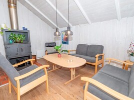 Una sala de estar acogedora con una mesa de madera, sofás grises y un sillón de cuero negro.