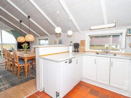 Una cocina moderna con armarios blancos, una isla central y un comedor con sillas y una mesa de madera.