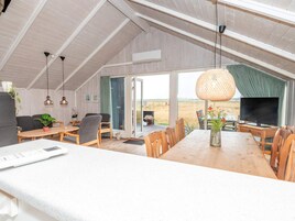 Un loft amplio con techo alto, un comedor con muebles de madera, un televisor y vistas al paisaje.
