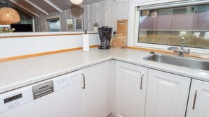 A compact kitchen with a dishwasher, a sink, and a window overlooking a building. - 6 Person Holiday Home in Harboore (Harboore)