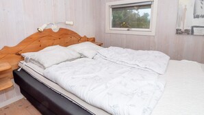 A bedroom with a wooden headboard, a window with a view, a bedside table, and a bed with a patterned duvet. - 6 Person Holiday Home in Harboore (Harboore)