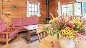 L’intérieur chaleureux d’un chalet avec des murs en bois, un canapé, une table à manger et une cheminée.