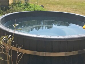A large, round, outdoor hot tub with a metal rim and a smooth, reflective surface.