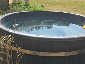 Un grand bain à remous extérieur, de forme ronde, doté d’un bord en métal et d’une surface lisse et réfléchissante.