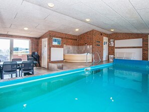 An indoor swimming pool with a brick wall, a hot tub, and a seating area with chairs. - 14 Person Holiday Home in Harboore (Harboore)