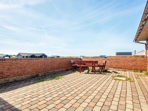 A patio area with a brick wall, a table with chairs, and a view of residential buildings in the background.