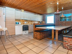 Une cuisine avec un plafond en bois, un mur en briques et une fenêtre donnant sur les montagnes.