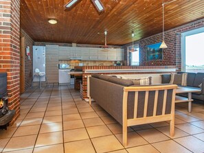 Un intérieur chaleureux avec une cheminée, un canapé, une table à manger et un coin cuisine.