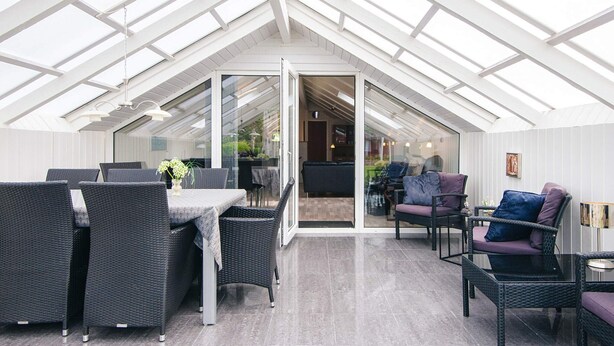 A spacious room with a high ceiling and skylights, furnished with wicker chairs and a dining table. - 8 Person Holiday Home in Hemmet (Hemmet)