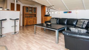 A modern kitchen with wooden cabinets, a black leather sofa, and a dining table. - 8 Person Holiday Home in Hemmet (Hemmet)