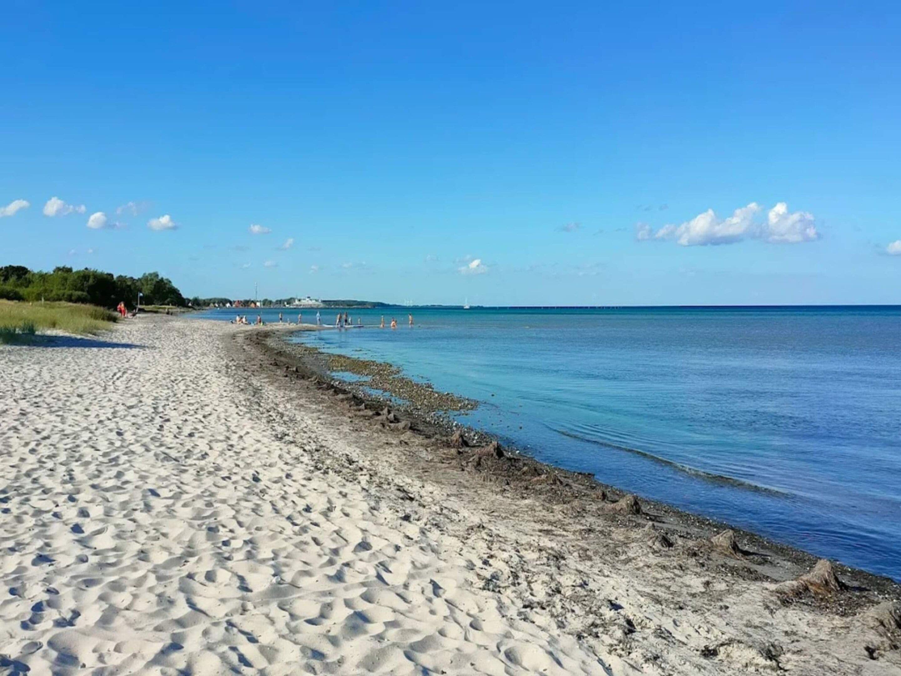 A sandy beach with clear blue water and a distant shoreline.