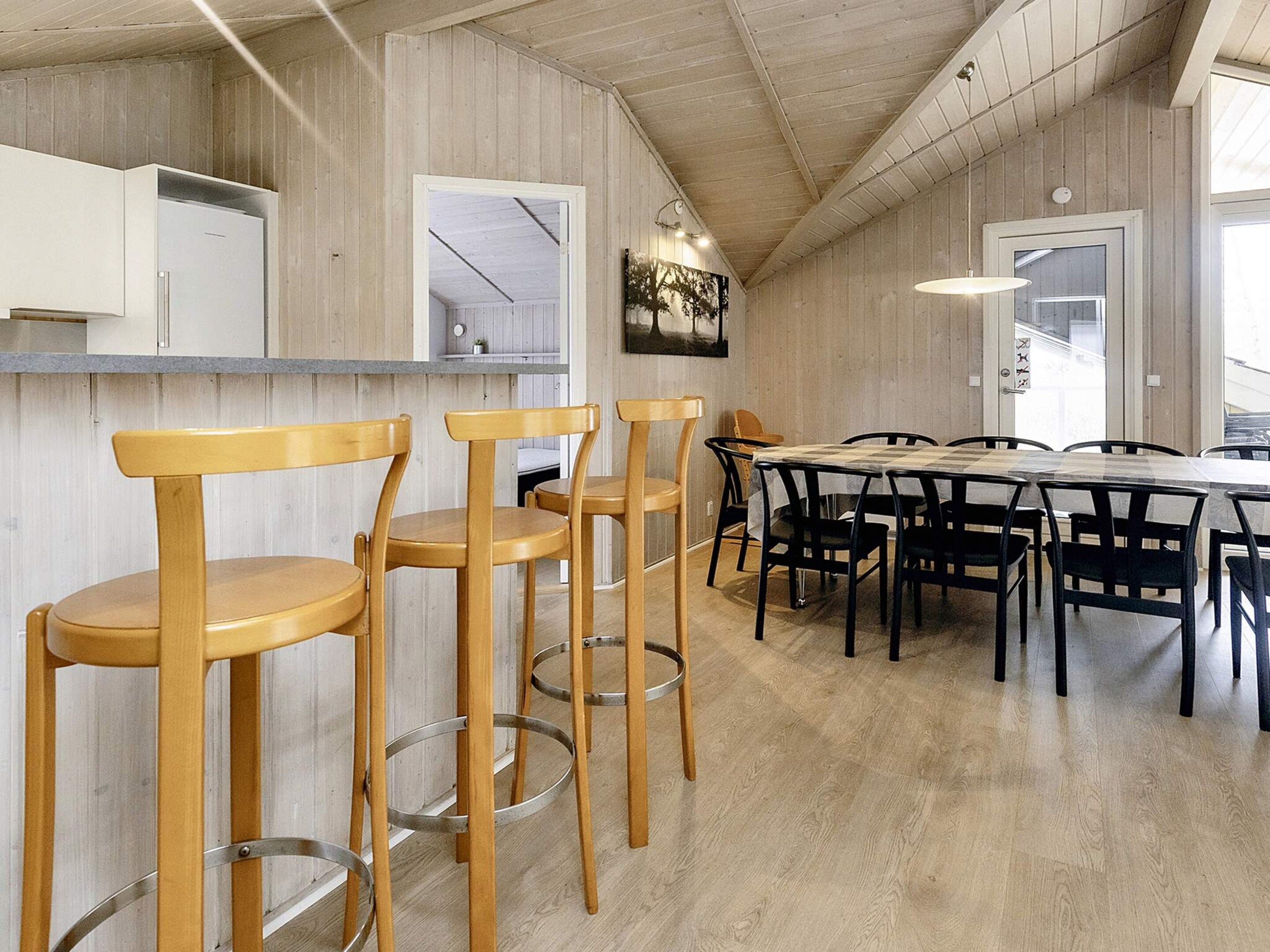 Een moderne keuken met houten barstoelen, een eettafel met stoelen en een groot raam.