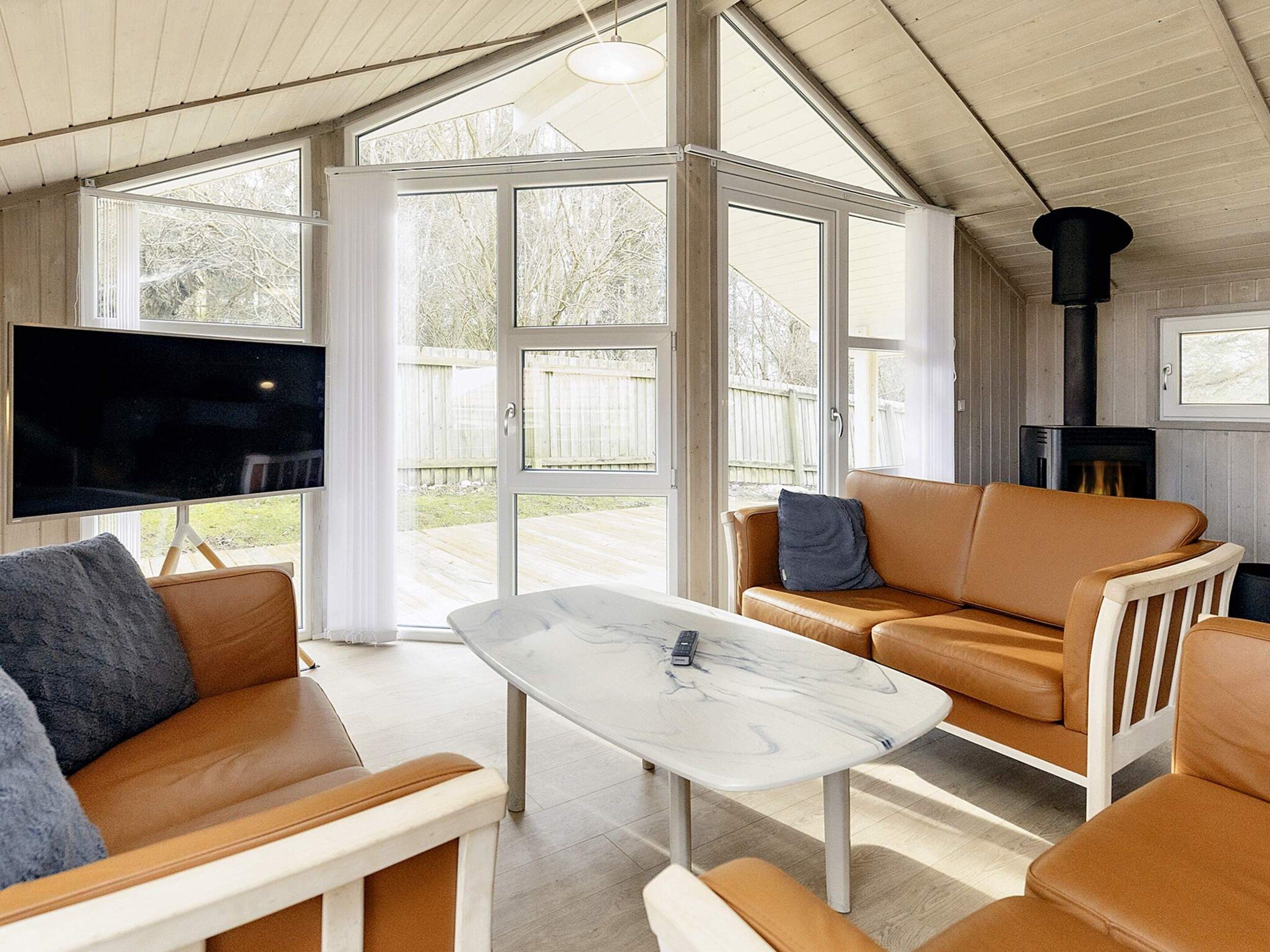 Een moderne woonkamer met een televisie, leren banken, een marmeren salontafel en een open haard.