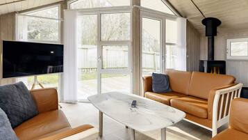Een moderne woonkamer met een televisie, leren banken, een marmeren salontafel en een open haard.