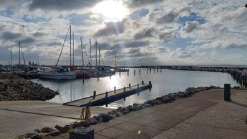A marina with boats docked, a pier extending into calm water, and a cloudy sky.