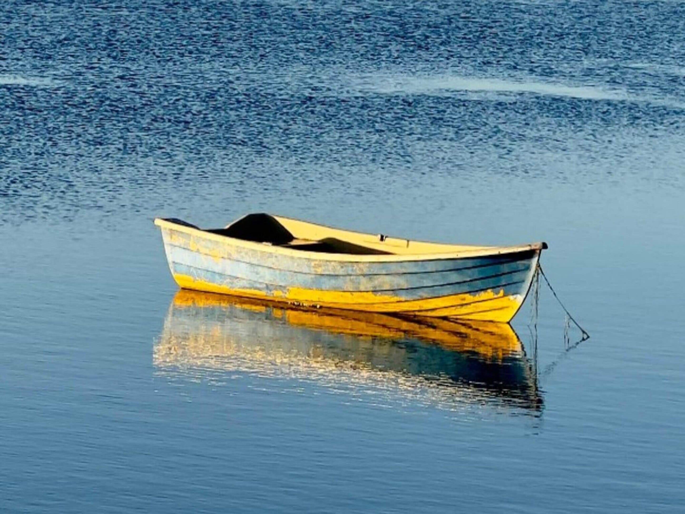 A small boat with a pointed bow and a cabin, floating on calm water.
