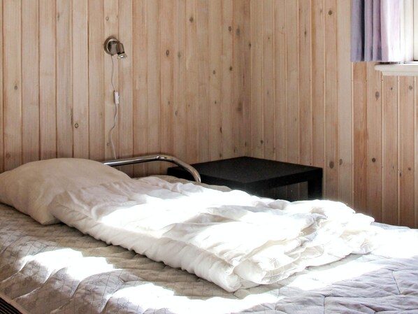 Un dormitorio con una cama, una mesita de noche y una lámpara de pared.