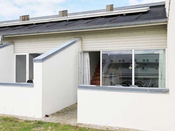 A single-story building with a flat roof, a visible chimney, and a window with a curtain.