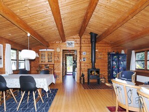 A wooden cabin interior with a dining area, a kitchen, a fireplace, and a view of the outdoors. - 4 Person Holiday Home in Sjaellands Odde (Sjællands Odde)