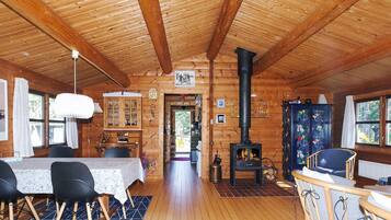 A wooden cabin interior with a dining area, a fireplace, and a view of the outdoors.
