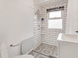 A bathroom with white subway tiles, a patterned floor, a window, and a shower area. - Elegant Holiday Home in Jutland With Whirlpool (Roslev)