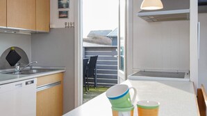 A modern kitchen with a countertop, sink, and cabinets. There are two mugs on the counter. - 6 Person Holiday Home in Lemvig (Lemvig)