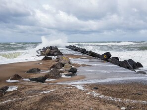 A rocky shoreline with waves crashing against a breakwater. - 6 Person Holiday Home in Lemvig (Lemvig)