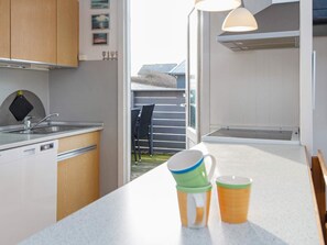 A kitchen with a sink, cabinets, and a countertop. There are two mugs on the counter. - 6 Person Holiday Home in Lemvig (Lemvig)