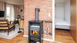 Una habitación con pared de ladrillo, chimenea, cama y zona de comedor.