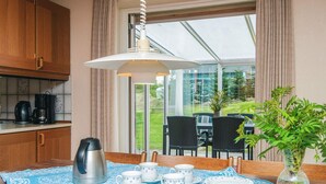 Un comedor con una mesa lista para cuatro, una cafetera y un florero con una planta.