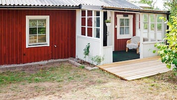 A red wooden building with a porch and a small deck.