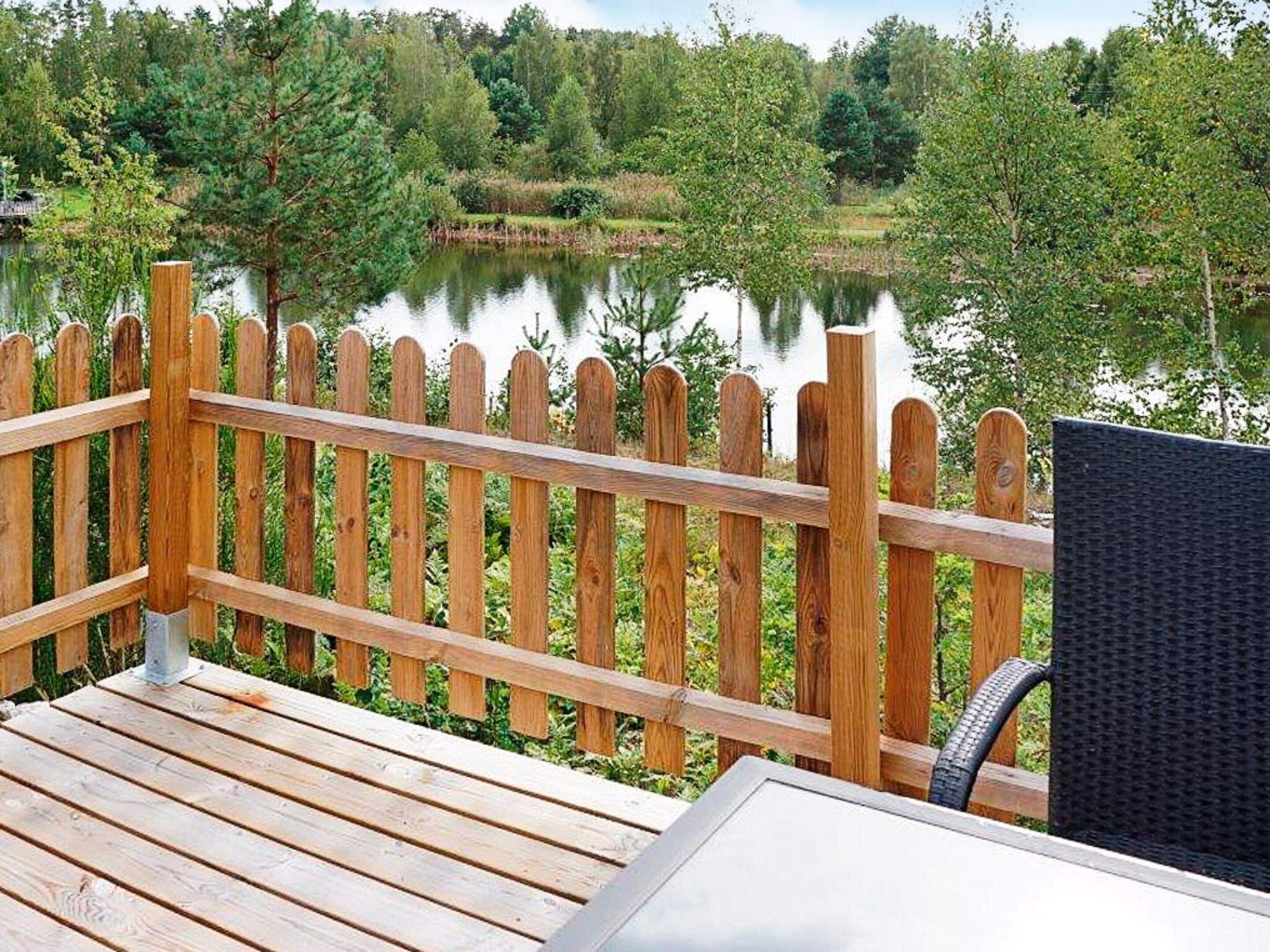 Eine Holzterrasse mit Blick auf einen See und umliegendes Grün.