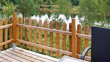 Eine Holzterrasse mit Blick auf einen See und umliegendes Grün.