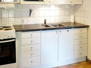 Une cuisine équipée d’une cuisinière, d’un évier et de placards.