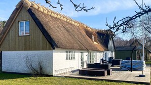 A traditional thatched-roof building with a wooden exterior, a small porch, and a flagpole. - 4 Star Holiday Home in Gedser (Gedser)