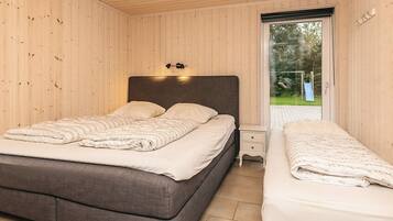 A bedroom with a large bed, a smaller bed, a nightstand, and a window with a view of the outdoors.