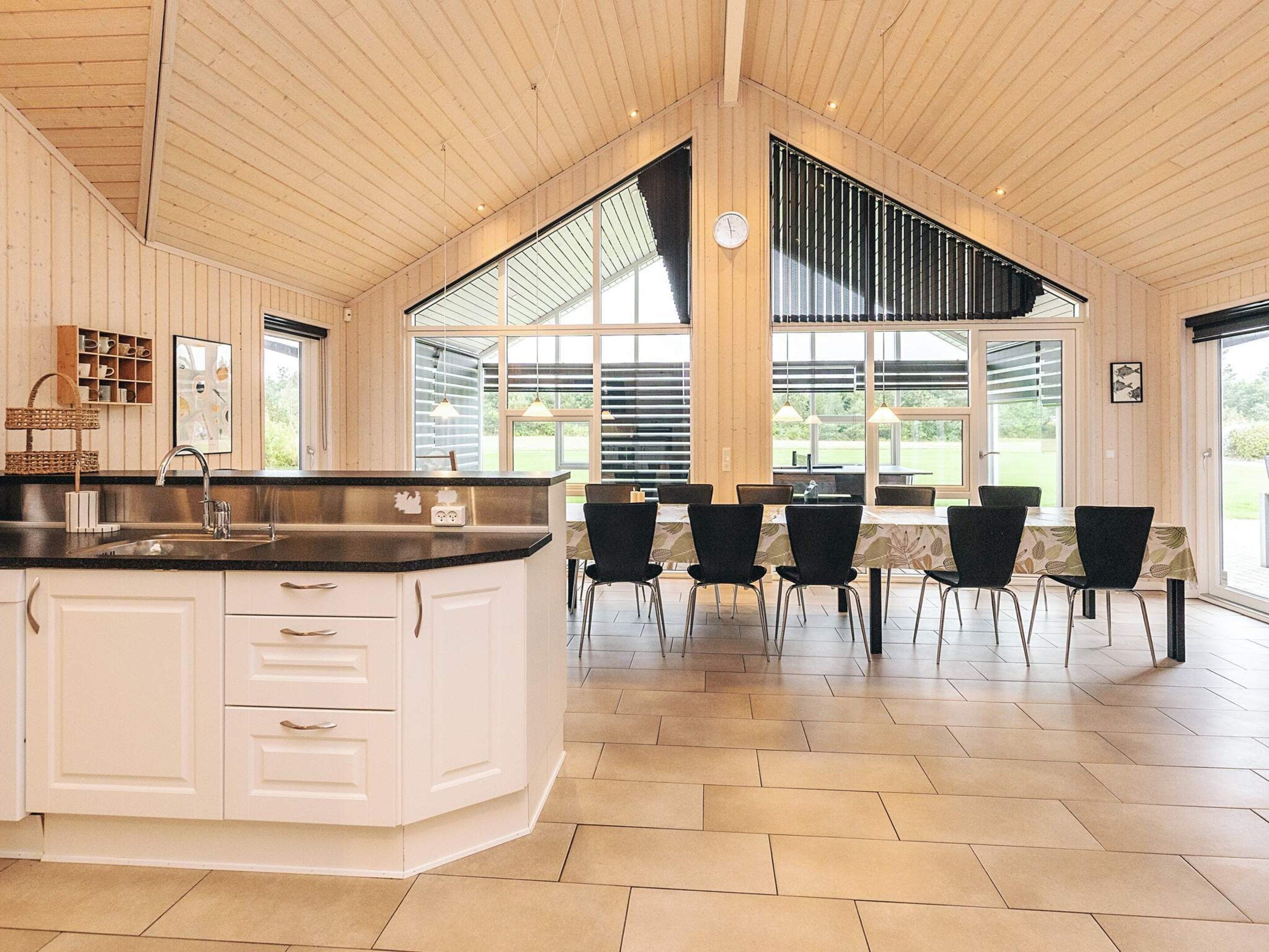 Una cocina amplia con una isla grande, electrodomésticos modernos y una zona de comedor con sillas y mesa.