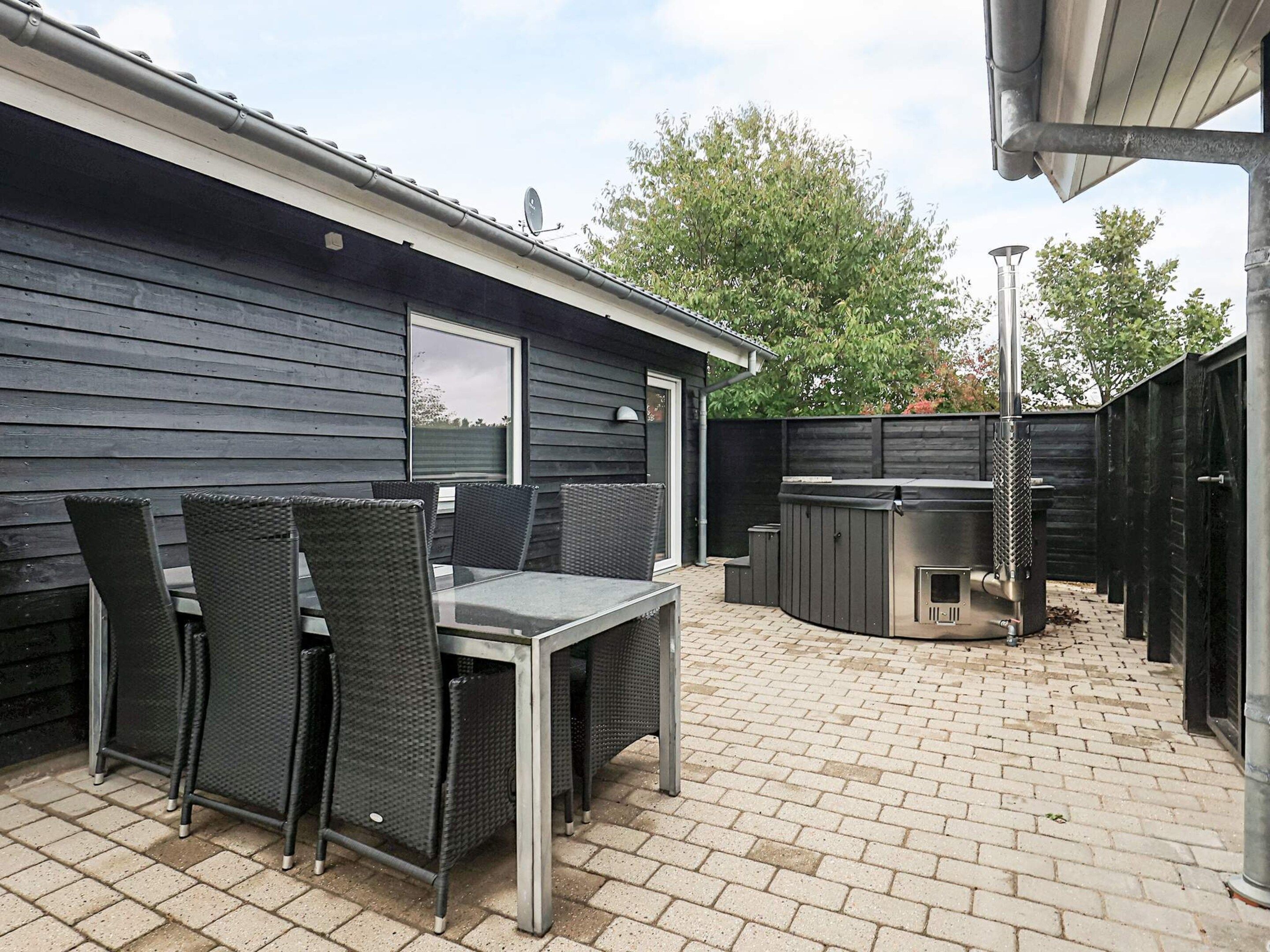 Un espace extérieur aménagé en patio, avec une table et des chaises, un barbecue et une zone délimitée par une clôture.