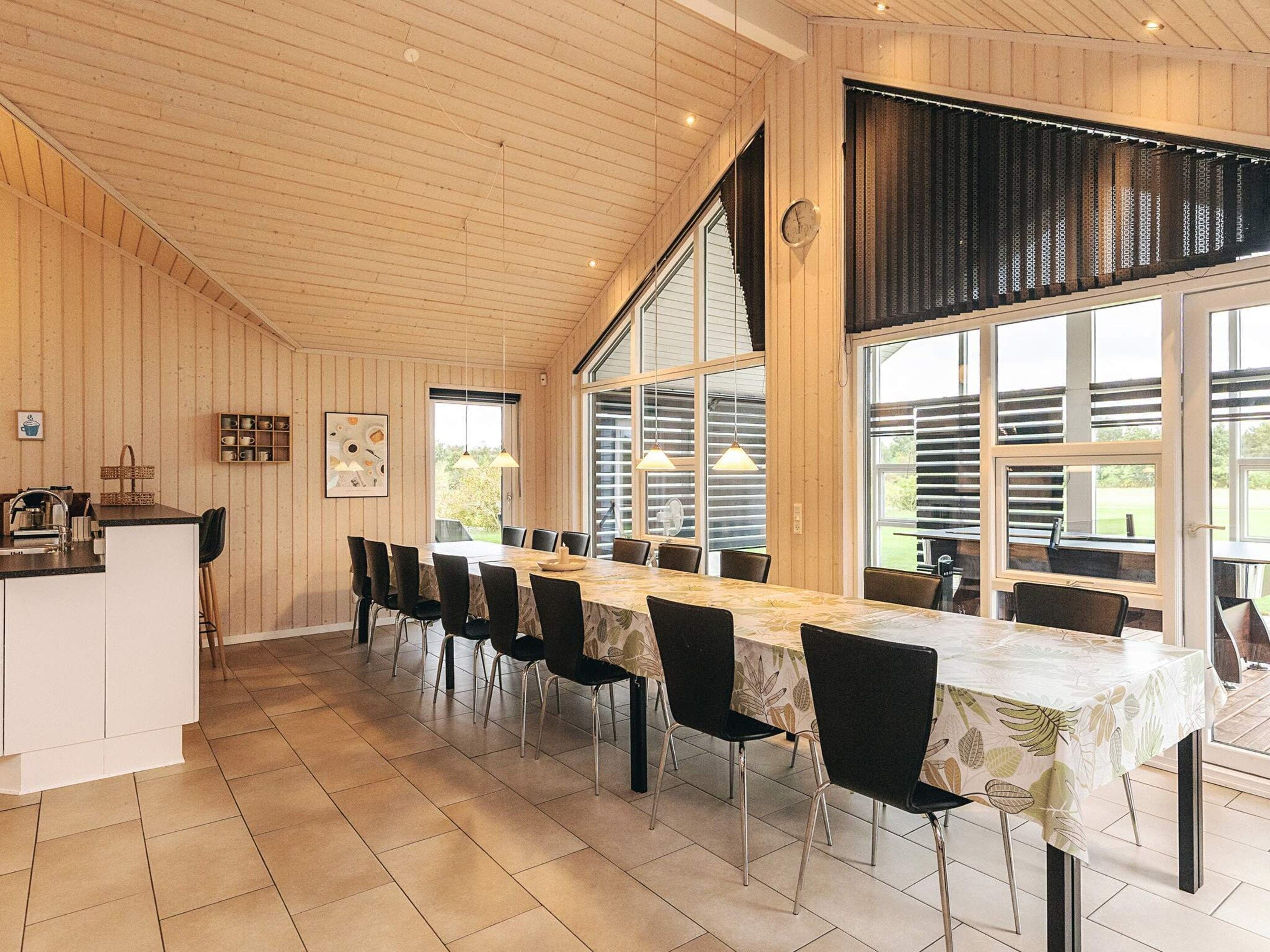 A spacious dining area with a long table, chairs, and a kitchen counter.