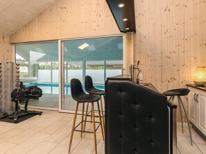 A modern interior with a pool, exercise equipment, and bar seating. - 5 Star Holiday Home in Hojslev (Hojslev)