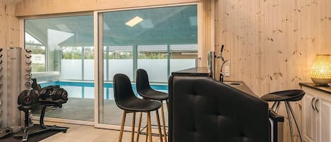 A modern interior with a pool, exercise equipment, and a bar area.