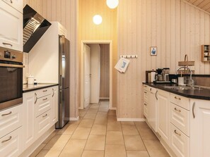 Une cuisine moderne avec des meubles blancs, un réfrigérateur en acier inoxydable et un plan de travail noir.