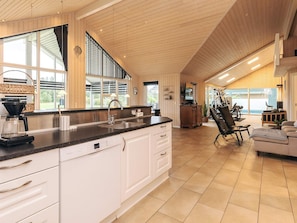 A spacious kitchen with a large island, a dining area with a high chair, and a view of the outdoors. - 5 Star Holiday Home in Hojslev (Hojslev)