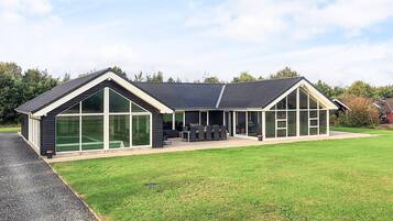 Une maison moderne à deux étages, dotée de grandes fenêtres et d’un patio couvert.