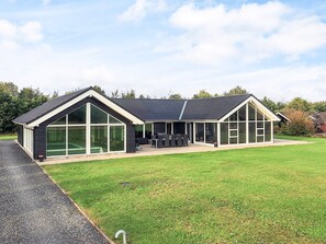 Une maison moderne à deux étages, dotée de grandes fenêtres et d’un patio couvert.