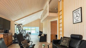 A spacious living area with a large TV, exercise equipment, and a Mercedes-Benz parking sign. - 5 Star Holiday Home in Hojslev (Hojslev)
