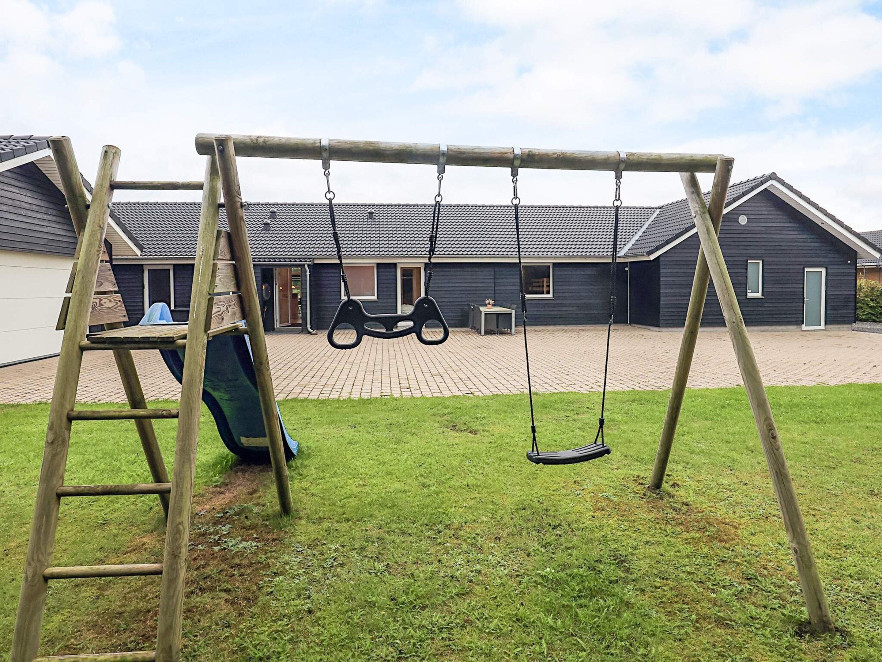 A wooden swing set in a backyard with a house in the background.