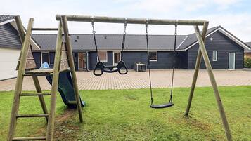 A wooden swing set in a backyard with a house in the background.